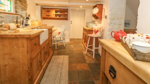 Una cocina acogedora con armarios de madera, encimera de piedra y un hervidor rojo.