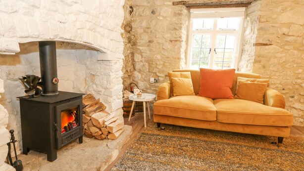 Una habitación acogedora con pared de piedra, chimenea, sofá y ventana.