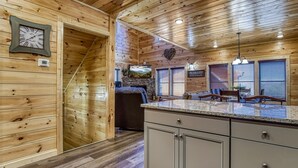 Un intérieur en bois comprenant un coin cuisine, une horloge et une cheminée en pierre.