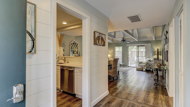 A spacious hallway with wooden flooring, a kitchen area with modern appliances, and a living room with a sofa and decorative items.