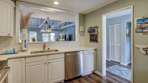 A modern kitchen with white cabinetry, a built-in dishwasher, and a large mirror above the sink.