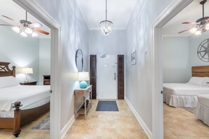 Ein Hotelzimmer mit einem Bett, einem Schreibtisch mit Lampe, einem Spiegel, einer Tür und einer Kristallleuchter.