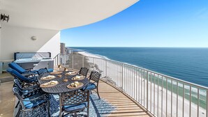 Een balkon met een ronde tafel, stoelen en een barbecue.