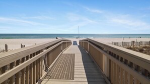 Un paseo marítimo de madera que lleva a una playa con cielo despejado.