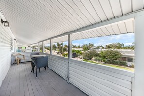 A covered outdoor area with a table and chairs, large windows, and a view of the neighborhood. - 🐾 Dog Friendly, Spacious Beach Retreat, only Steps to Sugary Sand, Conveniences and all the Fun! (Fort Myers Beach)