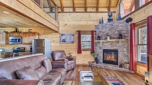 A cozy cabin interior with a living room featuring a leather sofa, a coffee table, and a fireplace.