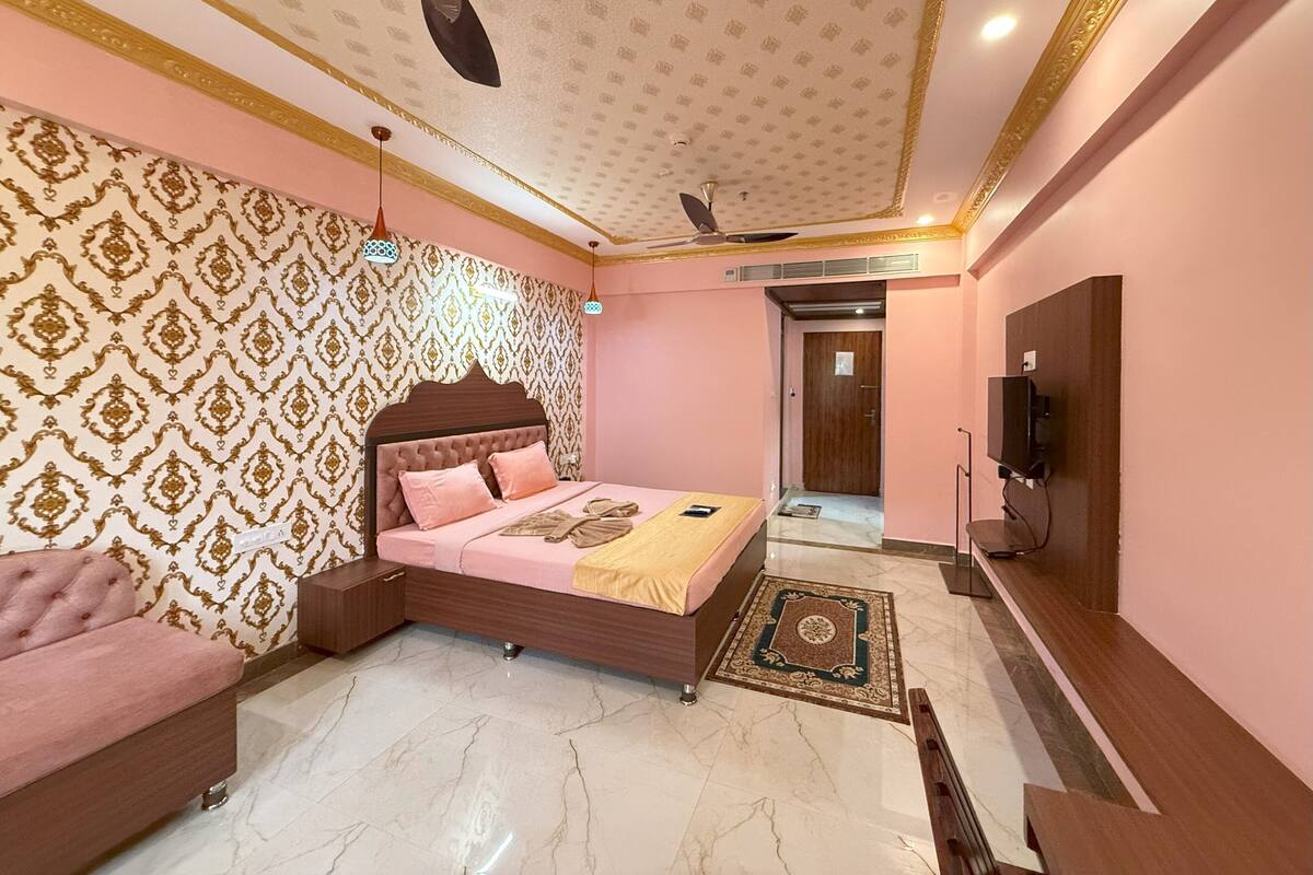 Een slaapkamer met een bed, een bank, een televisie en een plafondventilator.