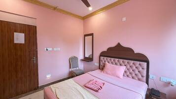 A bedroom with a bed, a ceiling fan, a chair, a nightstand, and a mirror.