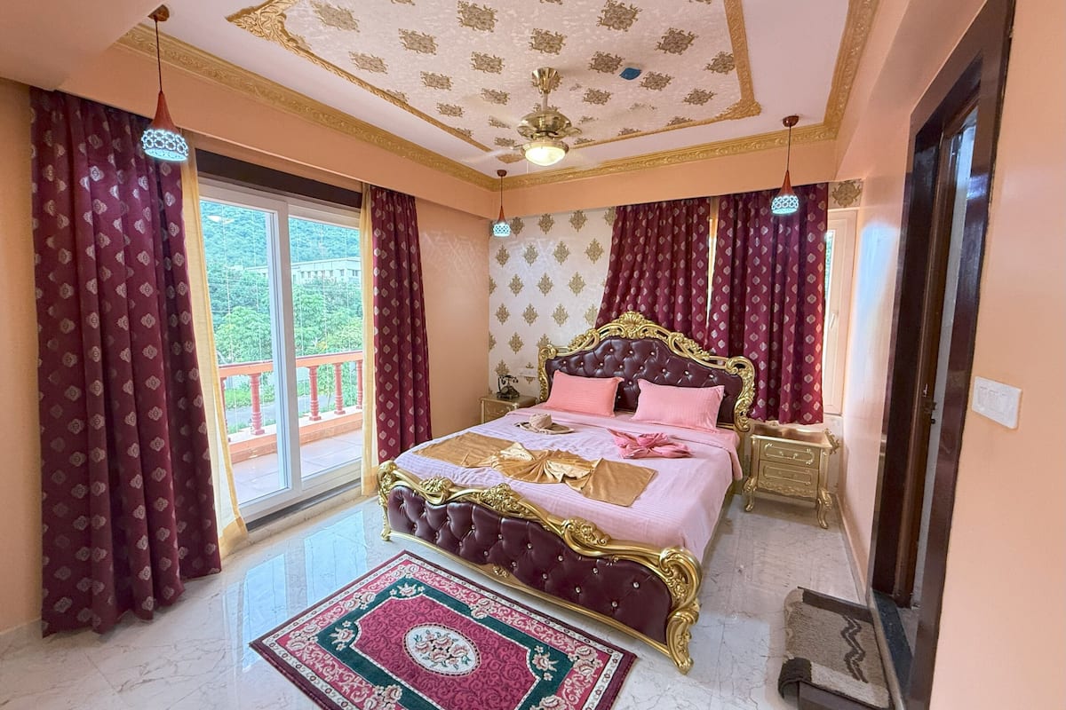 Een slaapkamer met een groot bed, een plafond met gedetailleerde patronen en uitzicht op groen.