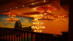 A grand chandelier in a hotel lobby with a mural of a woman on the wall.