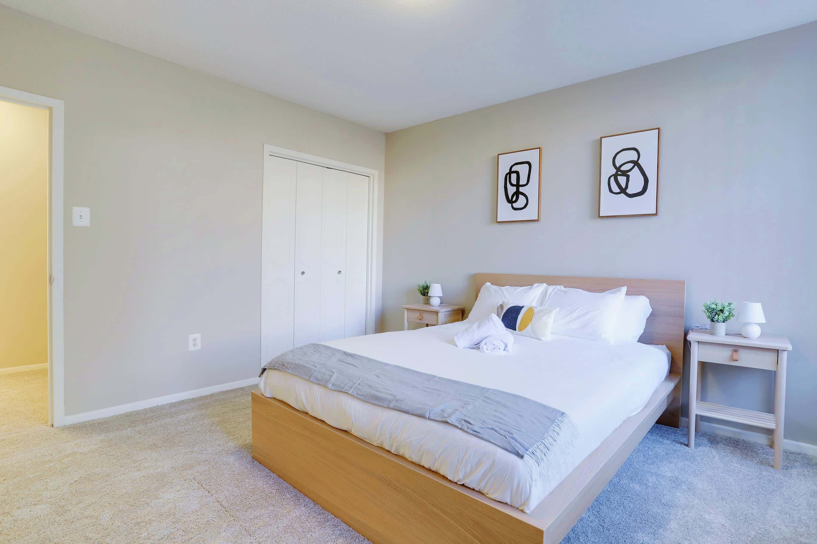 Una camera da letto con un letto, due comodini, un tavolino e due opere d'arte appese alla parete.