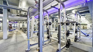 A modern gym with various weightlifting equipment, including squat racks and benches.