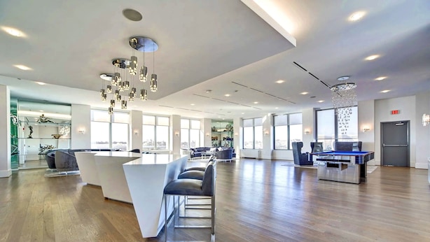A spacious lobby with a reception desk, seating area, and large windows offering city views.