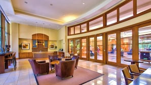 A spacious lobby with a reception desk, seating area, and large windows offering a view of the outdoor area.