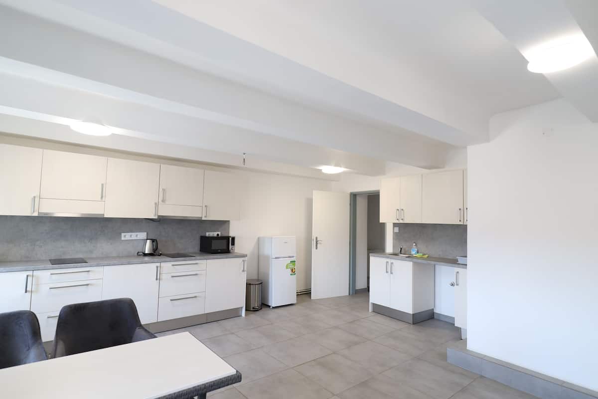 A modern kitchen with white cabinets, a microwave, a refrigerator, and a dining area with a table and chairs.