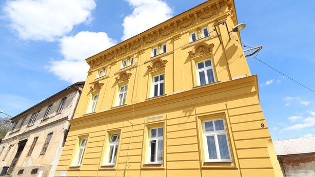 A yellow building with multiple windows and a sign above the entrance. - Apartmany a Hostel Plzen Rolnicke namesti (Plzen)