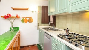 A kitchen with green cabinets, a stainless steel sink, and a gas stove. - Trilo Triglia Cala Reale 229 (Golfo Aranci)