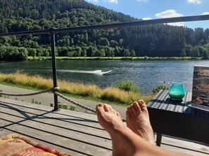Eine Holzterrasse mit Tisch, einem grünen Krug und einer Speisekarte.