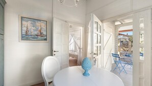 Ein Zimmer mit einem runden, weißen Tisch, einem blauen Dekorationsobjekt, weißen Wänden und einem Segelboot-Gemälde.