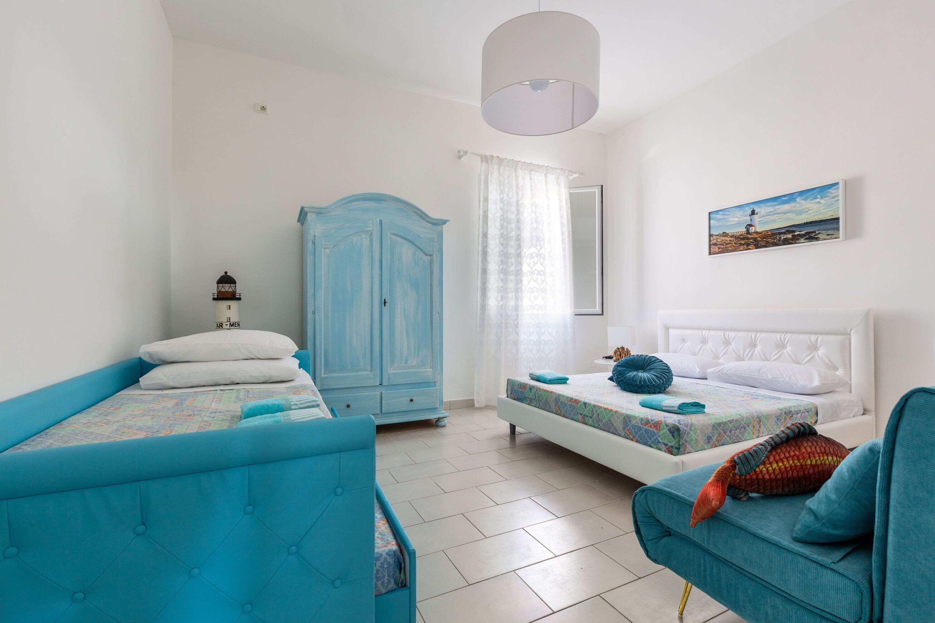 A bedroom with two beds, a wardrobe, and a painting on the wall.