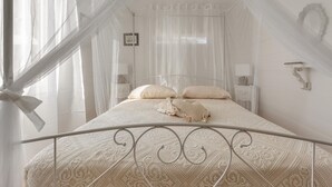 Ein Bett mit Baldachin, weiße Wände und ein kleiner Nachttisch mit einer Lampe.