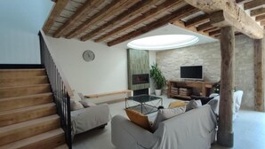 Un salon avec un escalier, une cheminée, un téléviseur et une table basse.