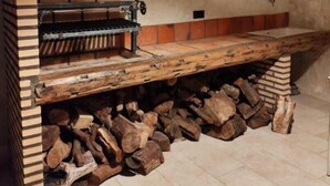 Une cuisine extérieure rustique dotée d’un four en briques, d’un plan de travail en bois et d’un plafond avec des poutres apparentes.