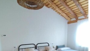 Une chambre avec deux lits, un plafond en bois et un luminaire suspendu.