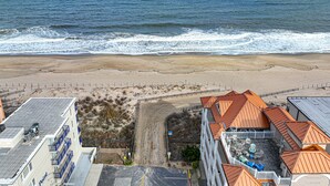 Um hotel à beira-mar com vista para o oceano, uma praia de areia e um parque de estacionamento.