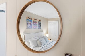 Ein Schlafzimmer mit einem runden Spiegel, einem Bett mit weißer Bettwäsche und drei Bildern an der Wand.