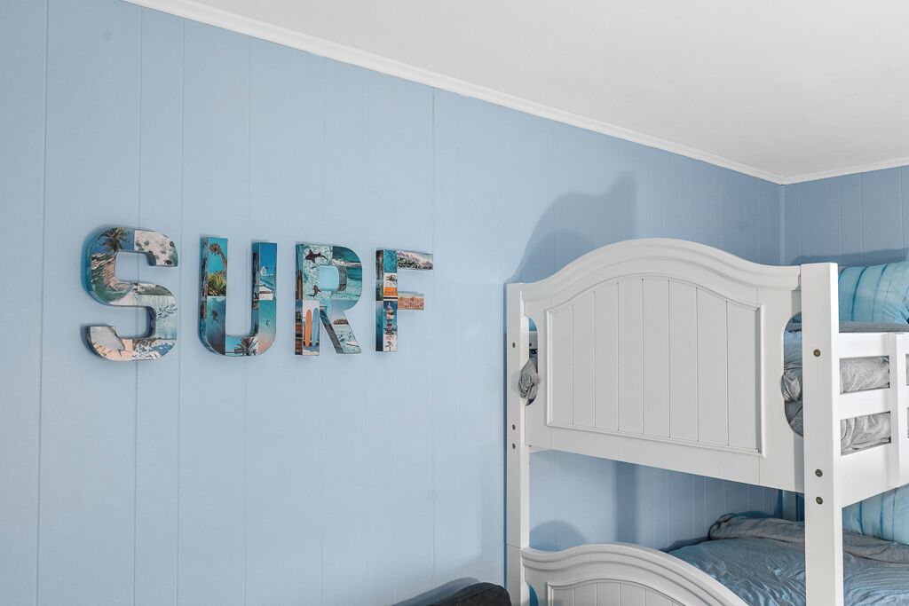 Ein Zimmer mit einem Etagenbett und einer Wand, auf der das Wort 'SURF' in dekorativen Buchstaben steht.