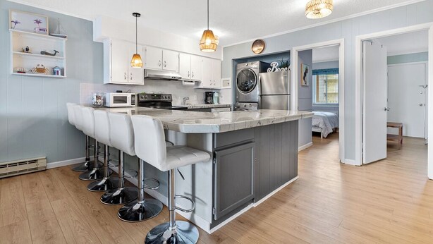 Cozinha moderna com ilha central, banquetas, forno embutido, micro-ondas e geladeira.