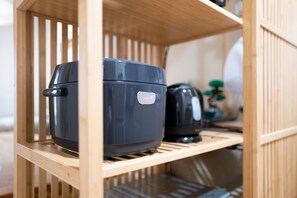 Une étagère de cuisine avec un appareil noir, peut-être un cuiseur à riz, et un présentoir en bois.