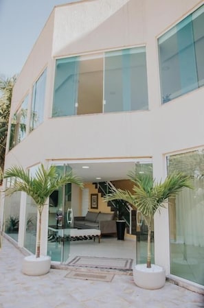 A modern two-story building with large windows, a glass entrance, and a well-maintained outdoor area with potted plants. - Pousada La Brisa (Itaguai)