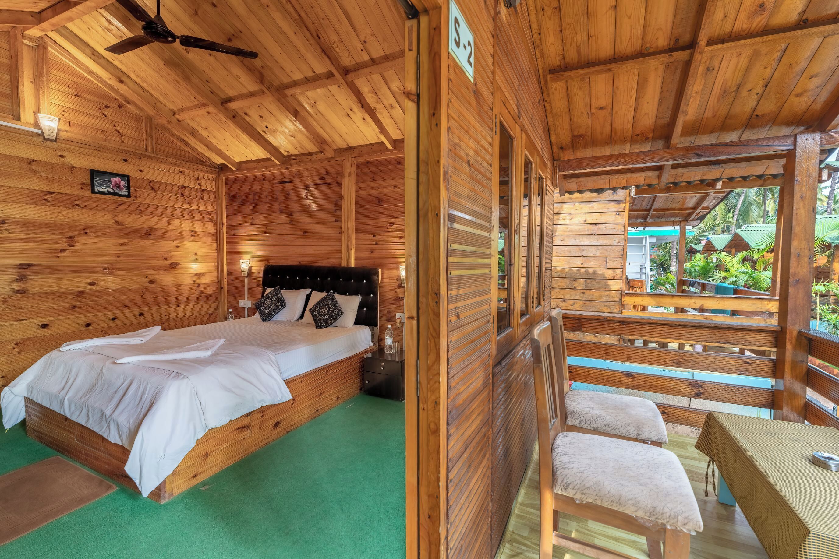 Une cabane en bois avec un lit simple, une petite table et un banc.