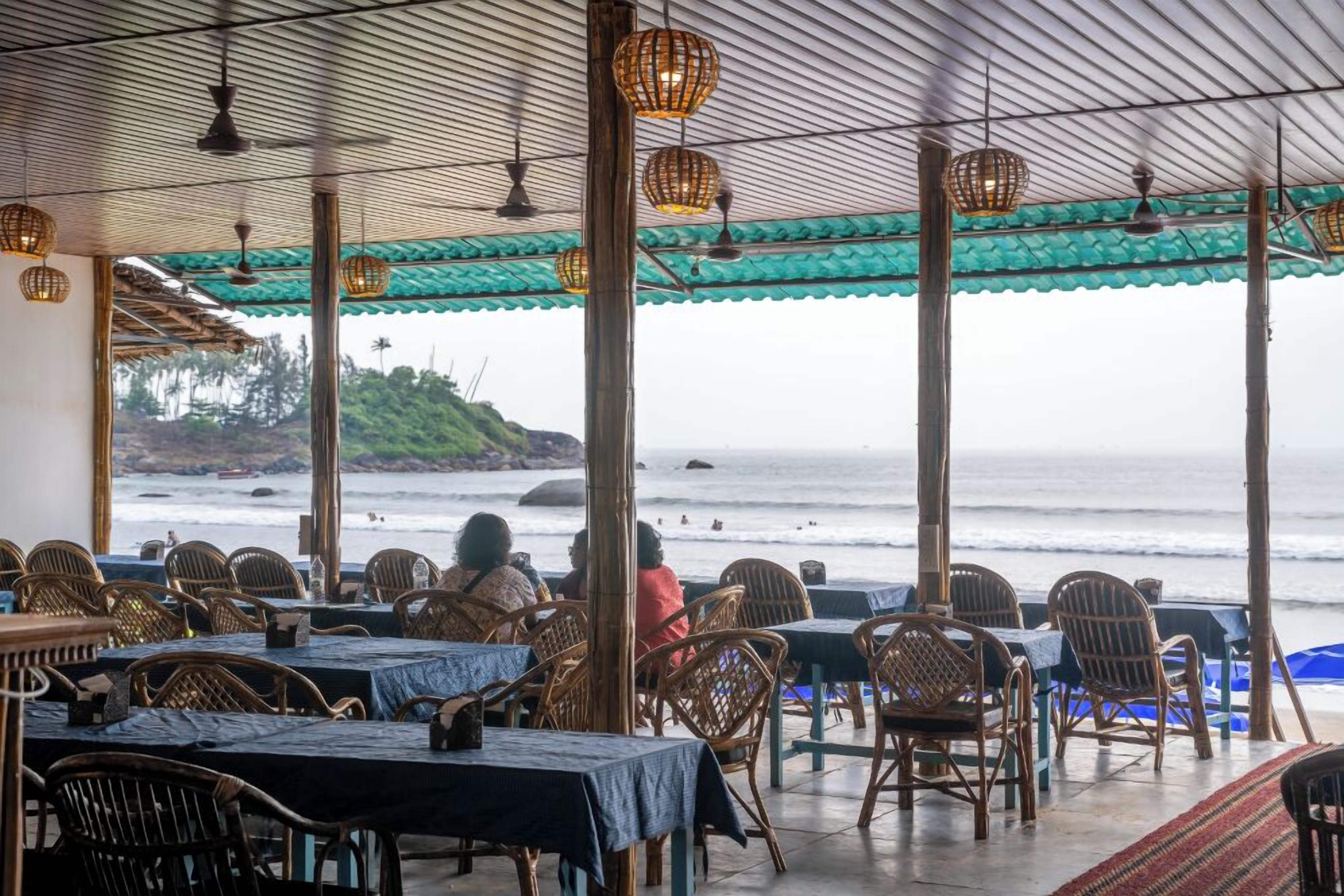 An outdoor restaurant with tables and chairs, overlooking the sea.