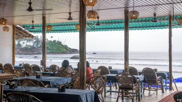 An outdoor restaurant with tables and chairs, overlooking the sea.