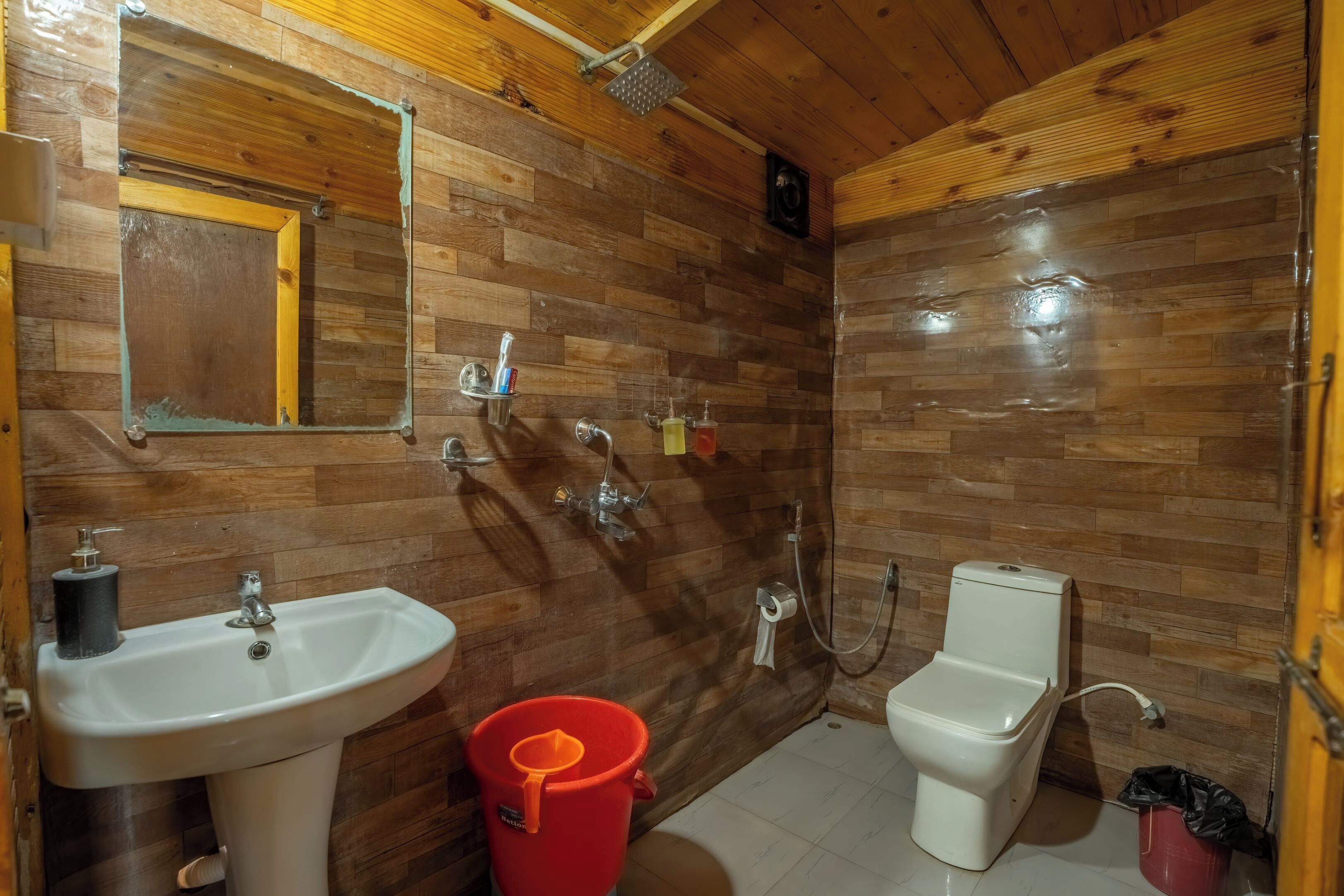 Un baño con paredes de madera, un lavamanos, un inodoro y una ducha.
