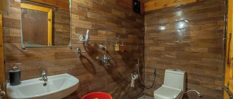 Un baño con paredes de madera, un lavamanos, un inodoro y una ducha.
