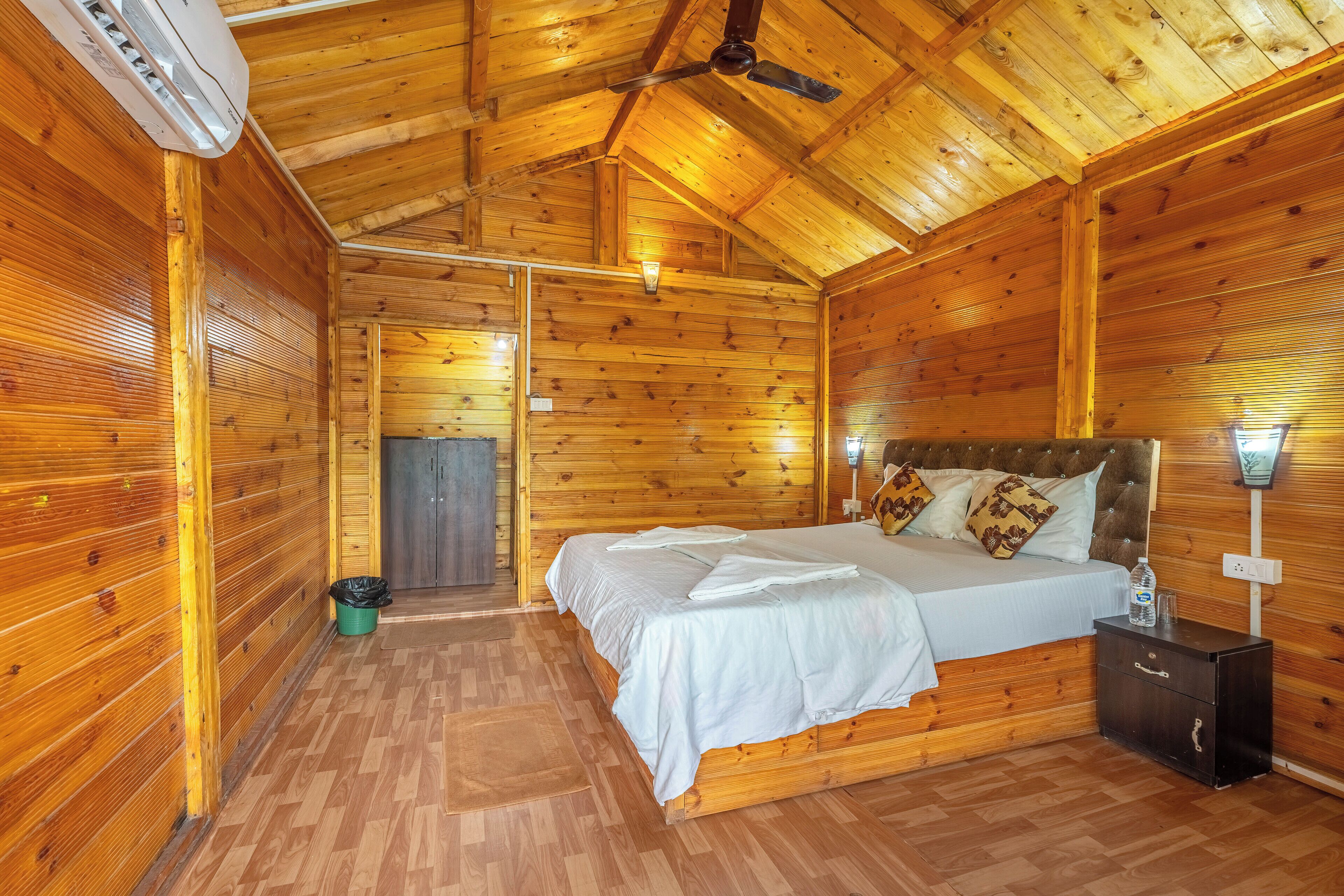 A wooden cabin bedroom with a bed, nightstand, and ceiling fan.