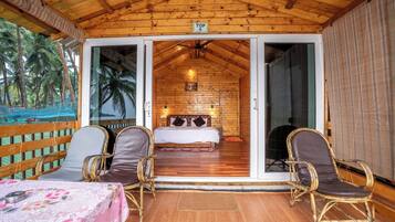 Una cabaña de madera con una cama, dos sillas y una mesa.
