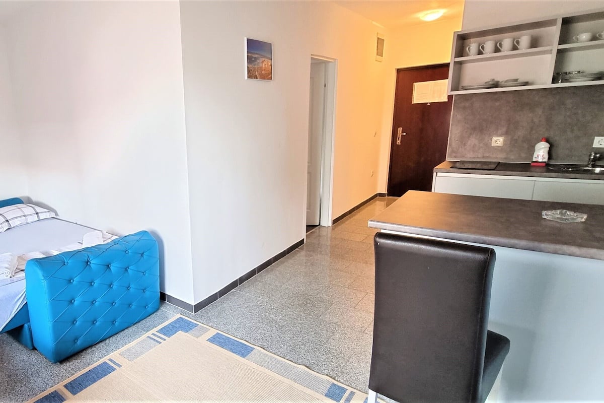 A compact hotel room with a bed, a small desk, and a kitchenette.