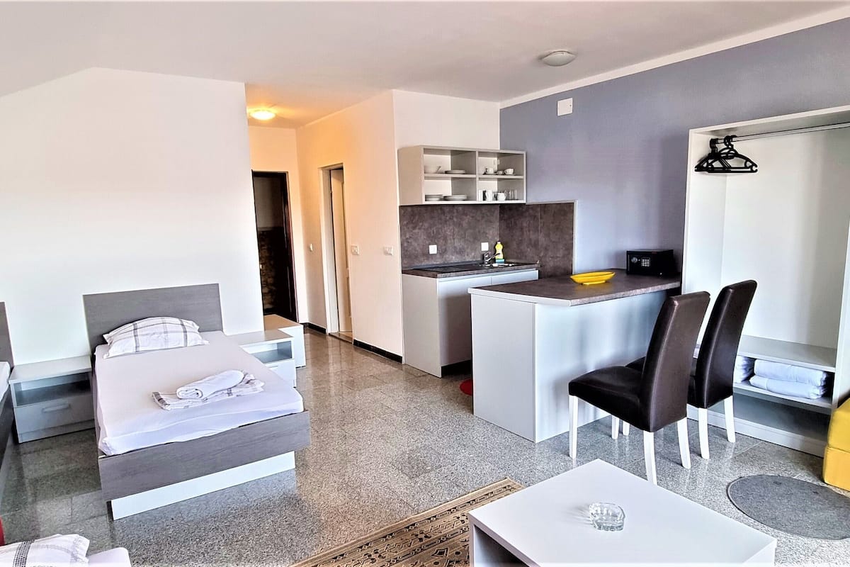 A hotel room with two beds, a small kitchenette, a dining area with a table and chairs, and a sofa.