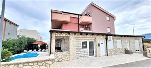 A two-story building with a stone facade, a swimming pool, and outdoor seating.
