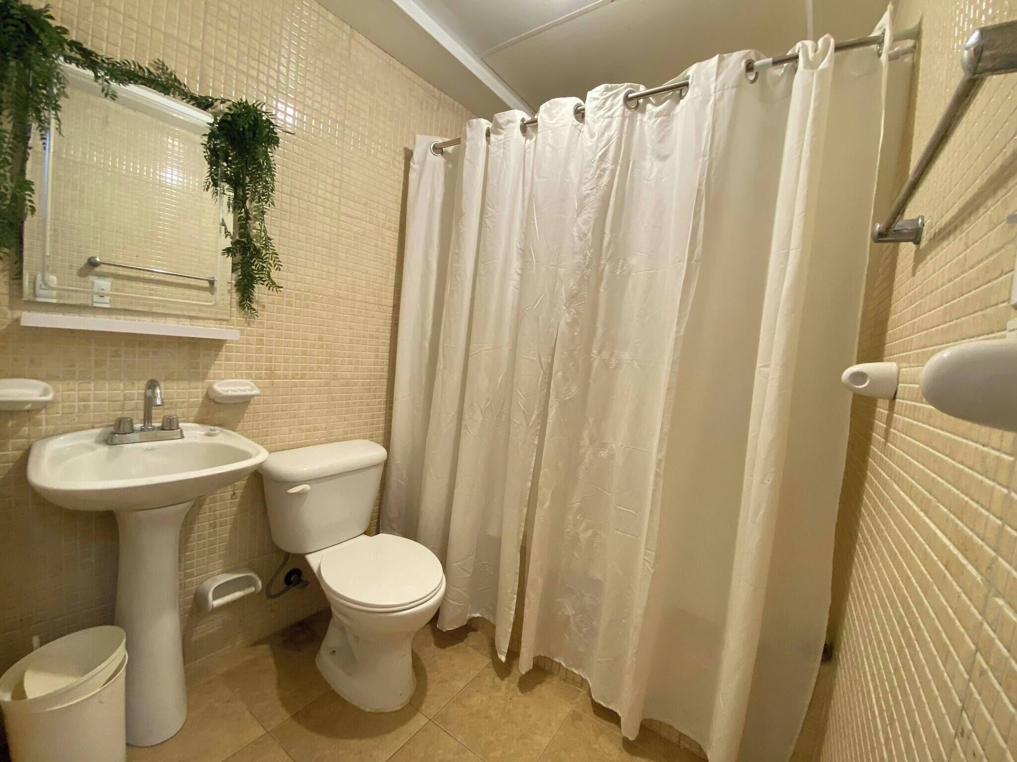 A bathroom with a white sink, toilet, and shower curtain.