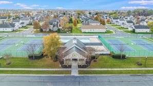 A residential area with houses, a central building with a clock, and tennis courts. - Beautifully Furnished Condo in Villages of Five Points (Lewes)