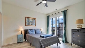 A bedroom with a bed, a nightstand, a dresser, a ceiling fan, a window with curtains, and a framed picture on the wall. - Beautifully Furnished Condo in Villages of Five Points (Lewes)