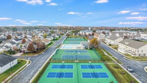 A residential area with houses, a tennis court, and a road. - Beautifully Furnished Condo in Villages of Five Points (Lewes)