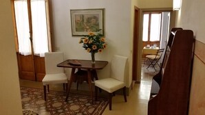 A dining area with a wooden table and white chairs, a vase with flowers, and a painting on the wall. - Dimora Pieri - Corsini Apartment, historic building  in the old center with lift and terrace (Firenze)