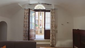 Un umbral abierto con vista a un patio, un teléfono y una lámpara fijada a la pared.
